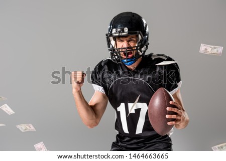 yelling American Football player with ball Isolated On grey with falling money