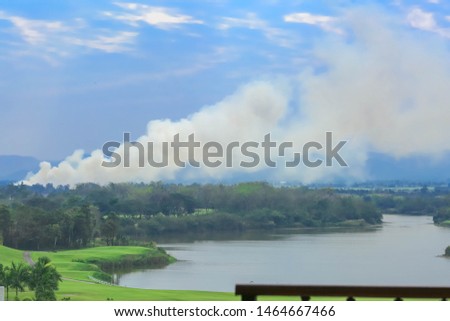 From the forest to the lake of the golf course There is a high smoke group rising from the burning. And looked at the sky with clouds in a color similar to smoke Background image That is landscape.