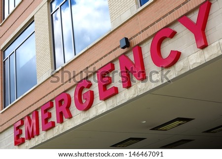 Red emergency room sign on the side of hospital with windows