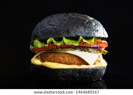 Delicious fast food. Modern black burger on black bacground. Toned picture