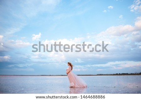 beautiful young pregnant woman enjoying the sun on the beach, pink lake