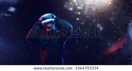 Young man in futuristic dress over dark magic light background. Guy in glasses of virtual reality. Augmented reality, game, hobby concept. VR.