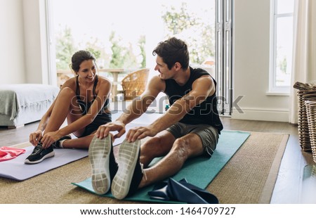 Couple exercising together. Man and woman in sports wear doing workout at home. Royalty-Free Stock Photo #1464709727