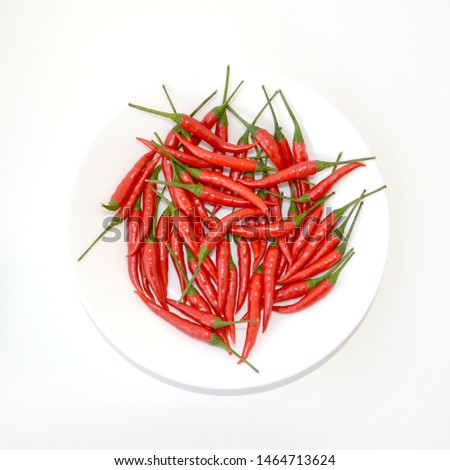Red hot chili peppers isolated on white plate. Upper view flat lay composition of colseup vegetables