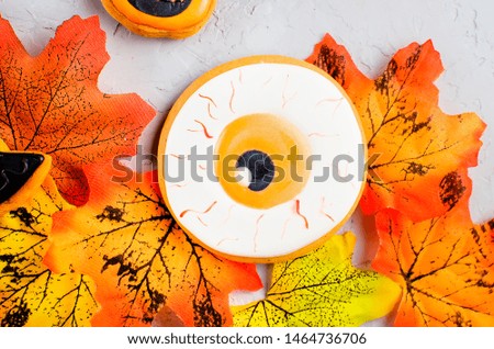 Halloween background with gingerbread cookies, pumpkin, candies and autumn leaves on on gray concrete background, copy space, top view, flat lay, mockup
