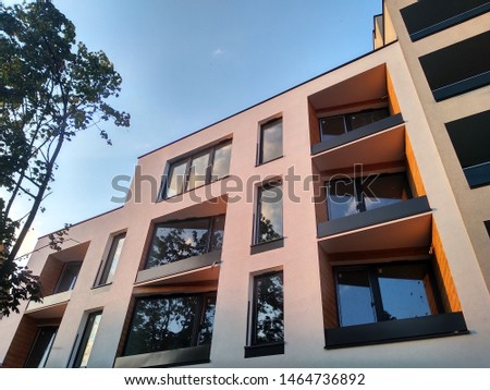 modern multi-storey residential complex in the city. Windows and loggias of a house at sunset among the trees. trends in construction, finishing of balconies with wood, the facade of the house Royalty-Free Stock Photo #1464736892