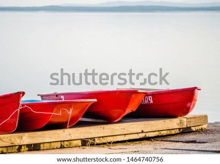 bright red boats lie on the wharf by the lake