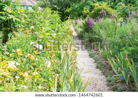 Gverny green garden with pathway and blooming borders
