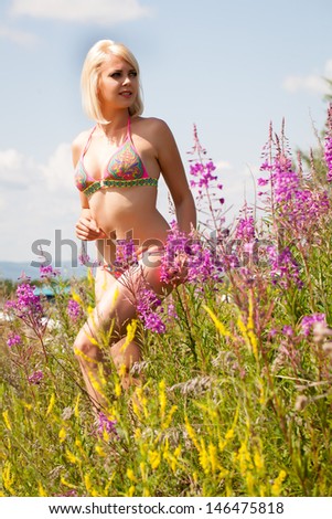 Beautiful young blonde woman among wildflowers