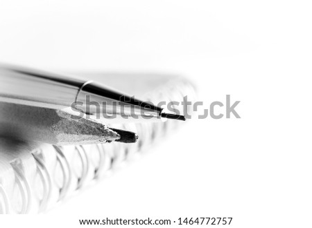 Black and white picture of 2 pencils, one old, one new, near each other, in diagonal, on top of a notebook with metal springs