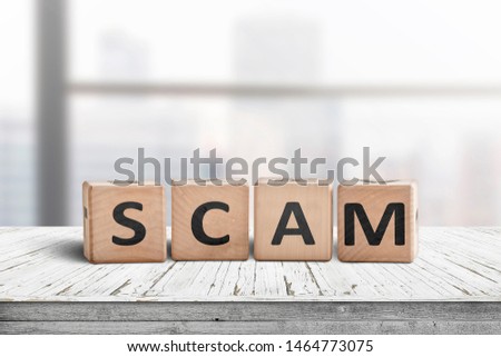 The word scam made of wooden blocks on a table in a bright office room