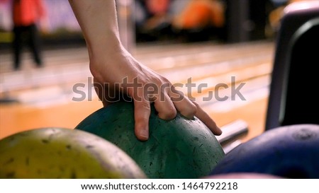 Close up for man hand taking a ball from a rack and throw it to the bowling lane. Media. The player throws a bowling ball that knocks down and rolls.