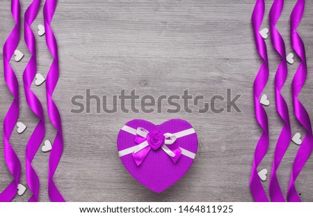 Gift box in the form of a heart. Ribbons in the form of a spiral and decorative heart. Place for text. Holiday concept. Background, copy space, top view.