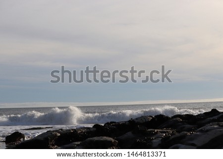 low tide with multiple rock formations and waves breaking in distance