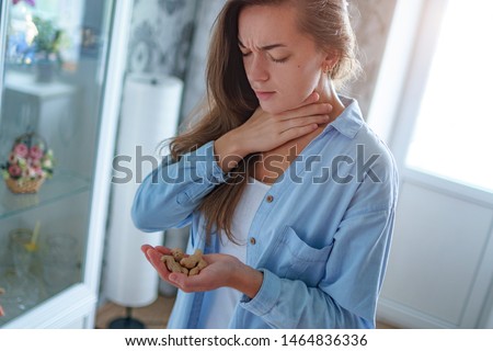 Young sick woman suffers from choking and cough from allergic reaction to peanut. Danger of nuts food allergy Royalty-Free Stock Photo #1464836336