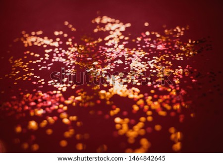 Abstract red background with gold confetti close up. Festive glitters backdrop. 