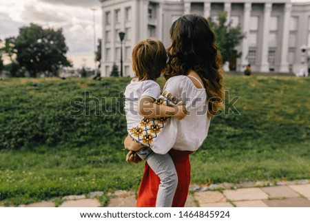 mother and son watching sunset in evening city, mother in traditional Ukrainian embroidered dress