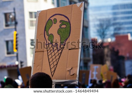 Protestor holds sign at ecological rally. A closeup view of a cardboard sign depicting planet earth melting on an ice cream cone. Conceptual placard held by environmentalist during protest.