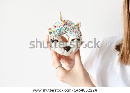 Unicorn donut in female hand. Trendy doughnut unicorn with white glaze. Copy space.
