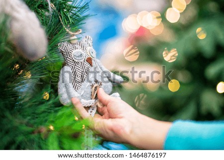 Children hands hold the decor at the Christmas tree on which the New Year's toys are hanging . Xmas concept.