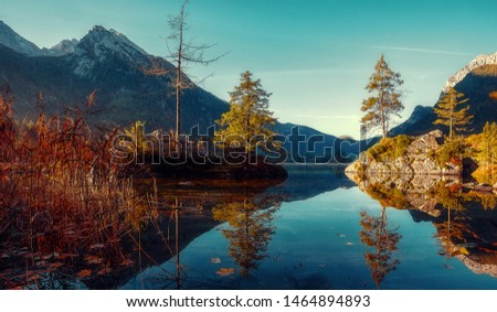 Awesome alpine lake during sunset. Scenic image of fairy-tale Landscape in sunlit with Majestic Rock Mountain on background. Wild area. Hintersee lake. Germany. Bavaria, Alps. Creative image