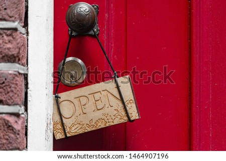 Wooden OPEN sign board hanging on the door, Red painted wood texture with vertical lines, Natural background.