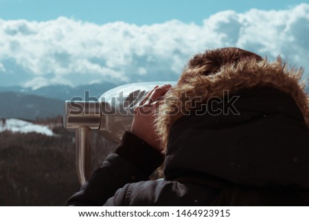 The guy looks through binoculars on winter mountains