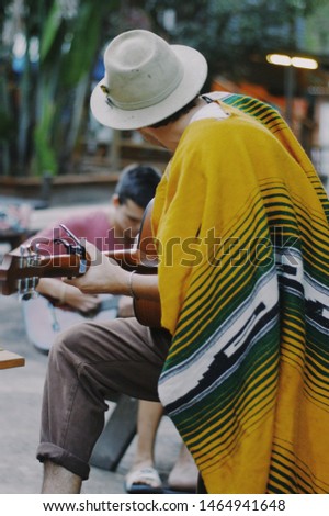 man playing guitar in yellow poncho