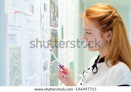 Young female student looking through job offers on board Royalty-Free Stock Photo #146497715