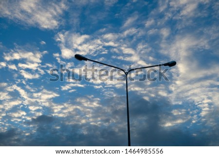 Blue sky background with clouds and silhouette of electric pole