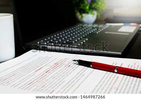 blur proofreading sheet on table with red pen and laptop Royalty-Free Stock Photo #1464987266