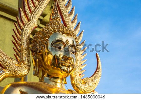 The golden Buddha face in outdoor of the temple in Thailand with the blue sky copy space 