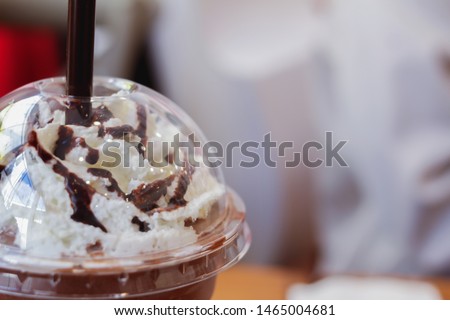 blurred photo,Blended iced coffee that is topped with cream and cocoa, served in a plastic glass and close the lid for the convenience of holding a coffee mug to drink outside the shop while traveling