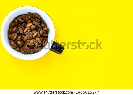cup with coffee beans and pink paper background
