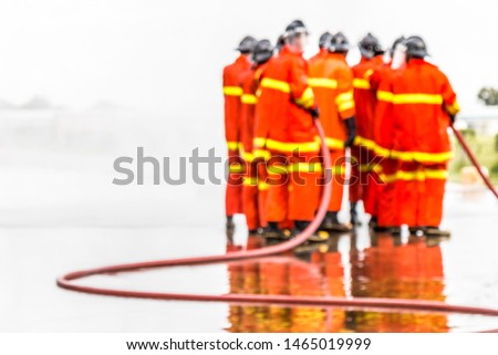 Blurred rear view of Firefighters group demonstration extinguish a fire during training in industry plant with sunlight. Fire in the industrial Factory, Rescue Teamwork concept.