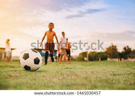 Action sport outdoors of kids having fun playing soccer football for exercise in community rural area under the twilight sunset sky. Picture with copy space.