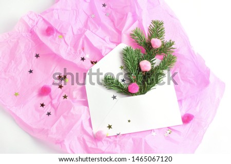 Christmas concept. composition on a pink background. white open envelope, spruce branches and multi-colored pompons shot from the top