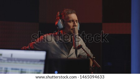 Medium shot of a male actor doing voice over in a sound studio