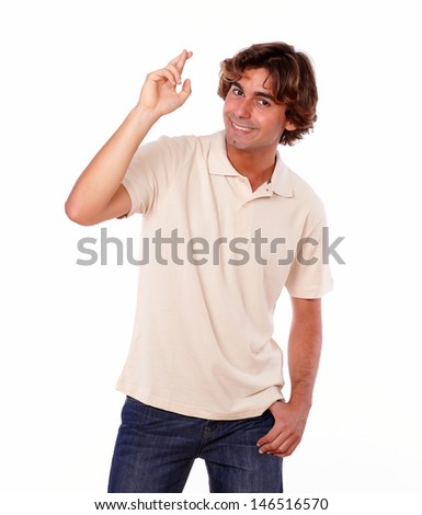 Portrait of an attractive smiling latin man crossing fingers while standing on white background