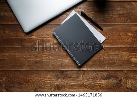 work space of a businessman. view from above . coffee black note and laptop on the desktop with black note. laptop on wooden background