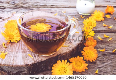 Herbal tea from calendula flowers in a transparent glass mug. Extract of tincture of calendula in the cup. Medicinal plants.