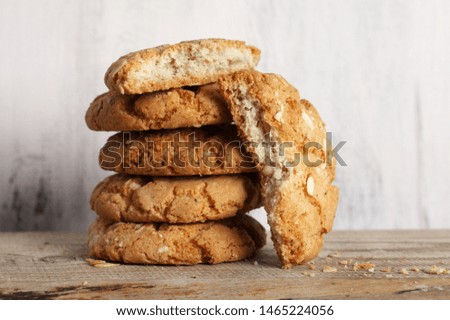Stack of whole and broken crumbly peanut cookies against rustic wooden background. 