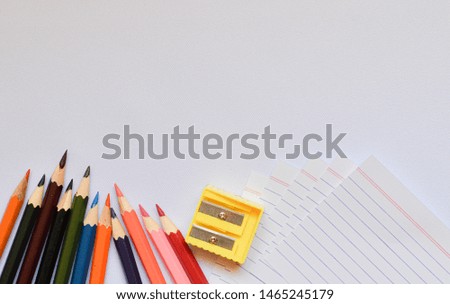 Artwork tools with coloring pencils, sharpener and paper on white background with space for text