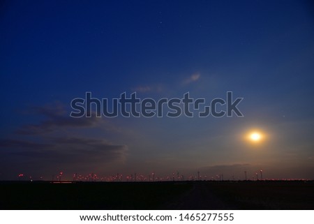 Full moon over the Burgenland plain with flashing red lights from wind turbines to generate green electricity at night in Austria.