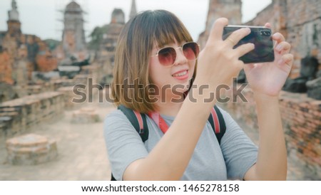 Traveler Asian woman using smartphone for take a picture while spending holiday trip at Ayutthaya, Thailand, female enjoy her journey at amazing landmark in traditional city. 