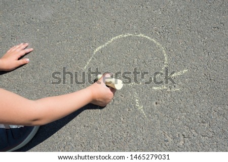 Children's hand with colorful chalk, draws on asphalt. Street art. Close-up child's hand.