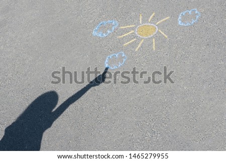 A children's drawing and the child's shadow on the asphalt. Colorful drawing on the asphalt road. View from above.