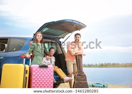 Happy family with luggage near car at resort