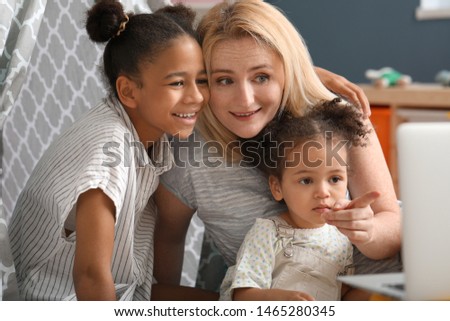 Happy woman and her African-American daughters with laptop at home