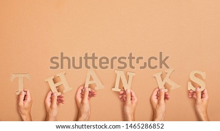 partial view of men holding word thank arranged from paper cut letters on beige background